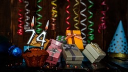 Birthday background with muffin and candles with number  74. Beautiful anniversary background with cake copy space with burning candles. Gift boxes with decorations.