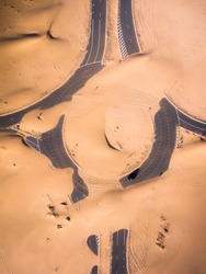Aerial shot of a car on a roundabout covered with sand from the desert
