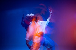 Cool dancing young mixed race girl in colorful neon studio light. Long exposure. Contemporary hip hop dance, rap rhythm