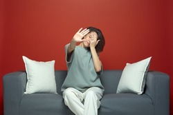 Young girl close eyes by hands, show stop gesture dont want to see disgraceful or scary movie or series sitting on couch