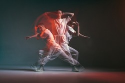 Dancing young sporty girl moving in fiery hip-hop dance in red neon studio light. Long exposure. Breakdancing school ad