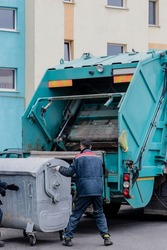 A garbage truck picks up garbage in a residential area. Workers load a container with garbage. Separate collection and disposal of garbage