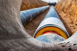 Insulated pipe. Large metal pipes with a plastic sheath laid in a trench. Modern pipeline for supplying hot water and heating to a residential area