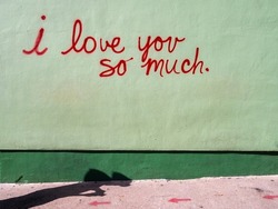Street art mural in red cursive writing on green background with a dark green line at the bottom 