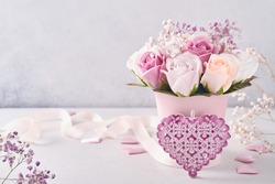 Festive composition with beautiful delicate roses flowers in pink round box on light gray background. Flat lay, copy space.