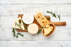 Set or assortment cheeses. Suluguni with spice, camembert, blue cheese, parmesan, maasdam, brie cheese with rosemary and pepper.  Top view. On white wooden old background. Free copy space.