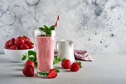 Strawberry smoothie or milkshake with berries and mint in tall glass on light grey background. Summer drink shake, milkshake and refreshment organic concept. Place for text.