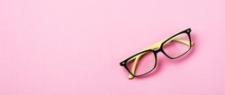 Modern spectacles eye glass or eyeglasses isolated on pink background. Top view. Banner. Mock up.