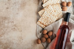 Passover celebration concept. Matzah, red kosher and walnut. Traditional ritual Jewish bread on sand color old concrete background. Passover food. Pesach Jewish holiday. 