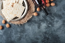 Passover celebration concept. Matzah, red kosher and walnut. Traditional ritual Jewish bread on old  dark grey concrete background. Passover food. Pesach Jewish holiday. 