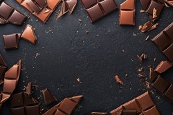 Chocolate pieces. Composition of bars and pieces of different milk and dark chocolate, grated and bean cocoa on black background. Baking Chocolate Texture.Top view with copy space. Mock up.