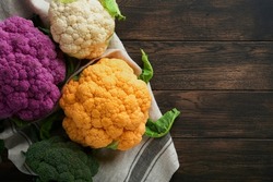 Colorfu cauliflower. Various sort of cauliflower on old wooden background. Purple, yellow, white and green color cabbages. Broccoli and Romanesco. Agricultural harvest. Mock up.
