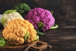 Colorful cauliflower. Various sort of cauliflower on old wooden background. Purple, yellow, white and green color cabbages. Broccoli and Romanesco. Agricultural harvest. Mock up.