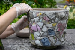 People decorate earthenware with mosaic techniques in the master class or in the fresh air in the workshop. Homemade mosaic flower pot with porcelain pieces.