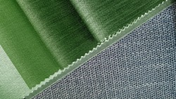 close up green tone fabric samples in catalog book matching with grey textile linen drapery fabric. combination of interior fabric samples for drapery or upholstery works.