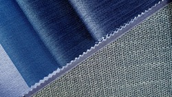 close up blue tone fabric samples in catalog book matching with grey textile linen drapery fabric. combination of interior fabric samples for drapery or upholstery works.