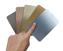 designer's hand choosing brushed metallic laminated samples containing  silver ,gold ,rose gold ,nigel and copper texture. set of multi color and texture of aluminum samples isolated on background.
