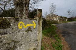Yellow arrow on the road to Santiago, indicating the direction to walk in the Way of St. James, Camino de Santiago, Spain.