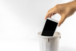 A man's hand throwing a smartphone in the trash. Image of digital detox