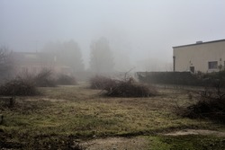Bare field with puddles and houses in the fog in the italian countryside