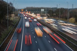 Fast moving traffic drives along the M42 in Warwickshire during evening rush hour, leaving traffic light trails as the vehicles are controlled using Active Traffic Management for each motorway lane