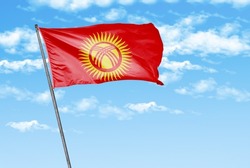 Kyrgyzstan waving flag on a sky blue with cloud background. - image