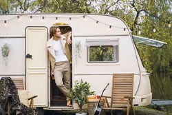 Young stylish american guy,man traveling in camper,house on wheels,trailer,motor home. Romantic road travel,freedom life. Campsite overnight in van. Wanderlust vacation,weekend. Happy adventure.