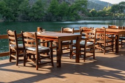 Wooden empty tables with chairs in restaurant on river bank.