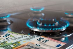 The banknotes lie next to a burning gas burner. The concept is to increase the cost of supply , payment for natural gas. The energy crisis. High cost, price of gas.