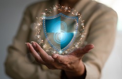 A businesswoman holds a shield protect symbol, which might be for an internet firewall, insurance, or a computer virus remover. Cyber security is a concept that protects your data.