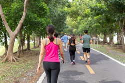 Woman exercise walking in the park with group people in blur background.