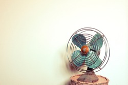 Old metal fan on white wall background vintage color