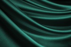   Blue green silk satin. Wavy soft folds. Shiny fabric surface. Luxurious emerald green background with copy space for design. Web banner. Birthday, Christmas, Valentine, holiday, festive.    