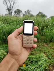 Farmer holding keypad mobile phone in hand with blank white screen