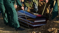 Burial. Men lower the coffin into the grave. n