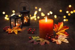 Lit candles with  autumn leaves and fall decoration.