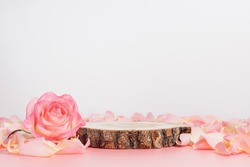 Wooden podium with pink rose and petals to demonstrate products, cosmetics and gifts. Valentine, mother day and women day concept