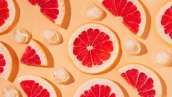 Grapefruit slices and melting ice cubes with harsh shadows background. Minimal concept, summer background, banner size