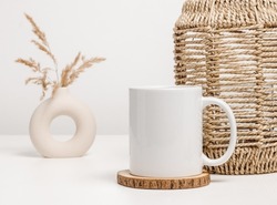 Mockup mug or coffee cup with home decor at the background. White mug for logo, text and design template. Aesthetic minimal concept