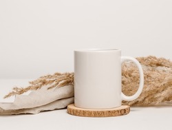 Mockup mug with linen cloth and dry pampas grass at the background. Mug for logo, text or design, minimal boho style