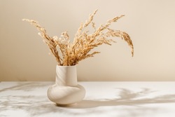 Beige ceramic vase with dry pampas grass and shadows on the table, scandinavian interior decoration, aesthetic style, copy space