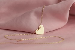 Gold jewelry on a pink background. Gift for Valentine's Day. Pleasure girlfriends, women, wives. Preparing for Valentine's Day. Pure pink background, fabric. earrings, ring, diamonds, chain