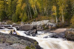 Visitors to local waterfalls on Current River admiring thundering water and fall colors. The area is called Cascades Conservation Area and is located in Thunder Bay, Ontario.