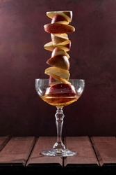 Creative composition with rose apple cider in a glass and apple slices on a brown wooden table