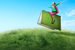 Asian little girl with eyeglasses sitting on a flying book. World Book Day