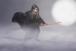 Old witch in a cloak flying on a broomstick in the night with full moon background. Scary witch Halloween concept