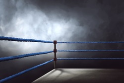View of a regular boxing ring surrounded by blue ropes spotlit by a spotlight
