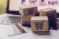 Online shopping - Paper cartons or parcel with a shopping cart logo and credit card on a laptop keyboard. Shopping service on The online web and offers home delivery.