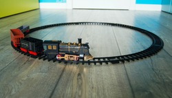 Closeup of a retro toy train on the circular track on the floor of colorful kids room