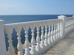 Anapa, Russia 23 August 2021. Balustrade overlooking the sea, sky and horizon, a fence consisting of a row of curly posts of balusters connected by a horizontal beam. Railing from curly white posts.